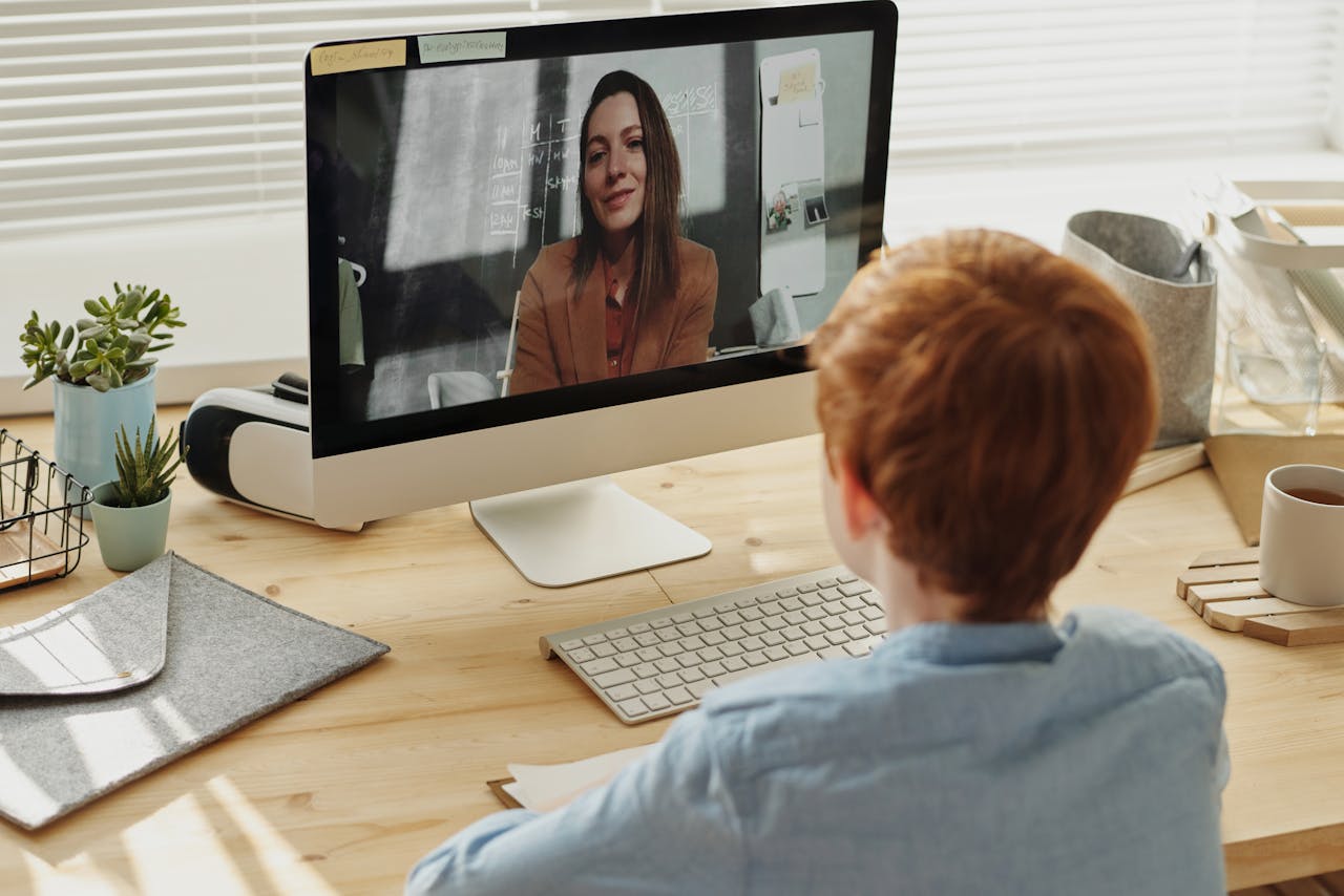 A child participating in an online class at home, focused on the educational content displayed on a desktop computer.