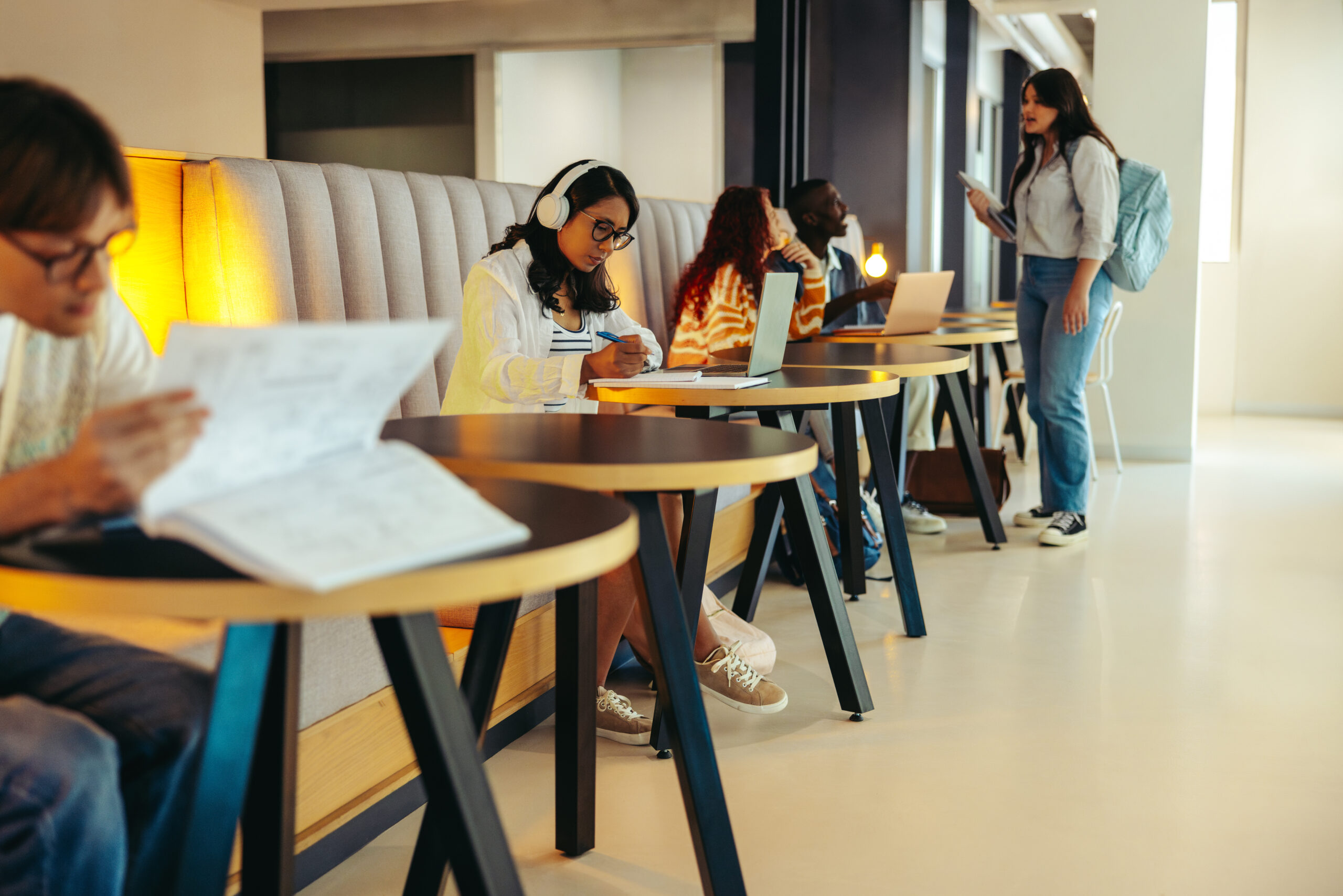 students studying in a modern school hallway with laptops and books, illustrating focus and collaboration