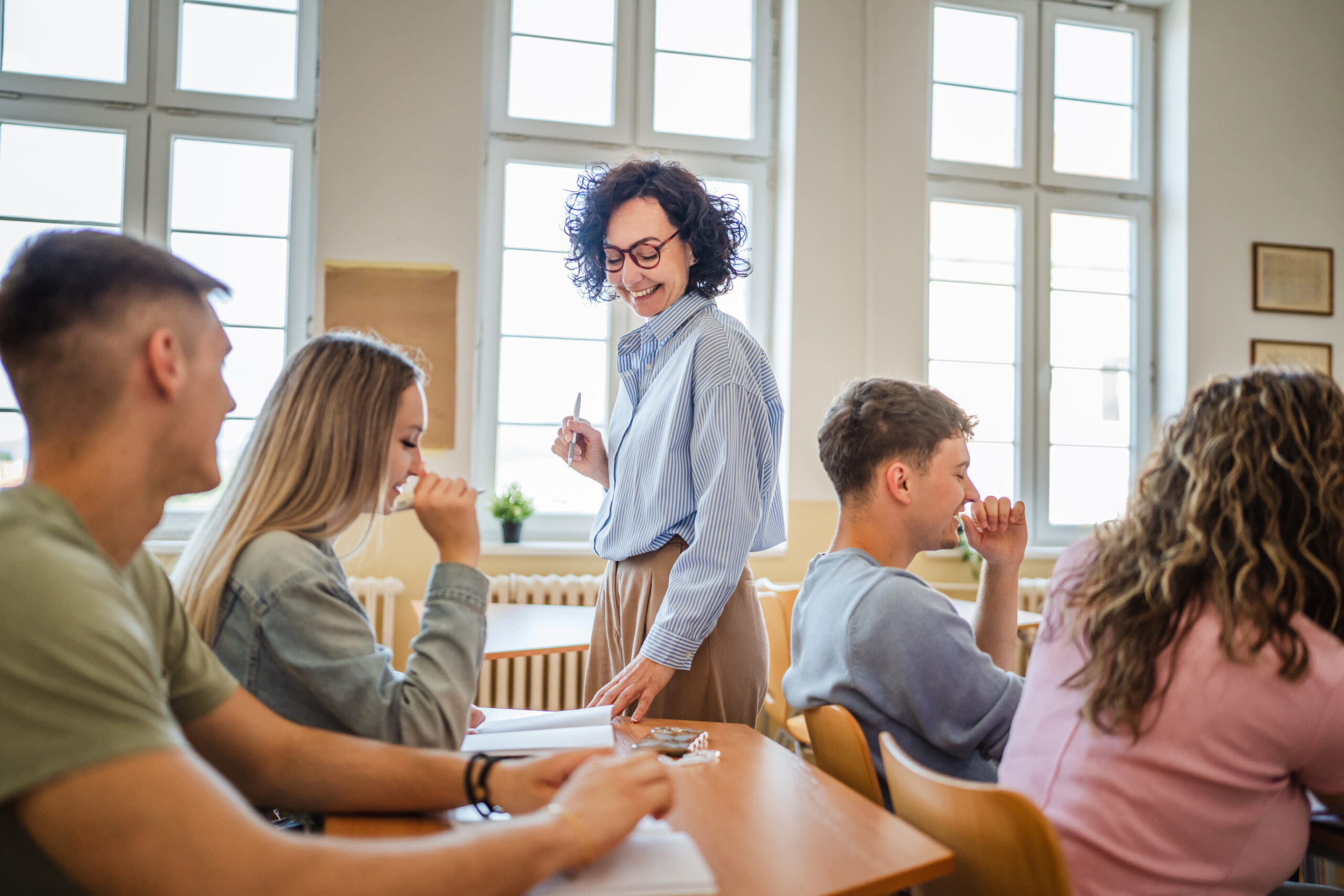 female teacher help high school students do exercises in classroom