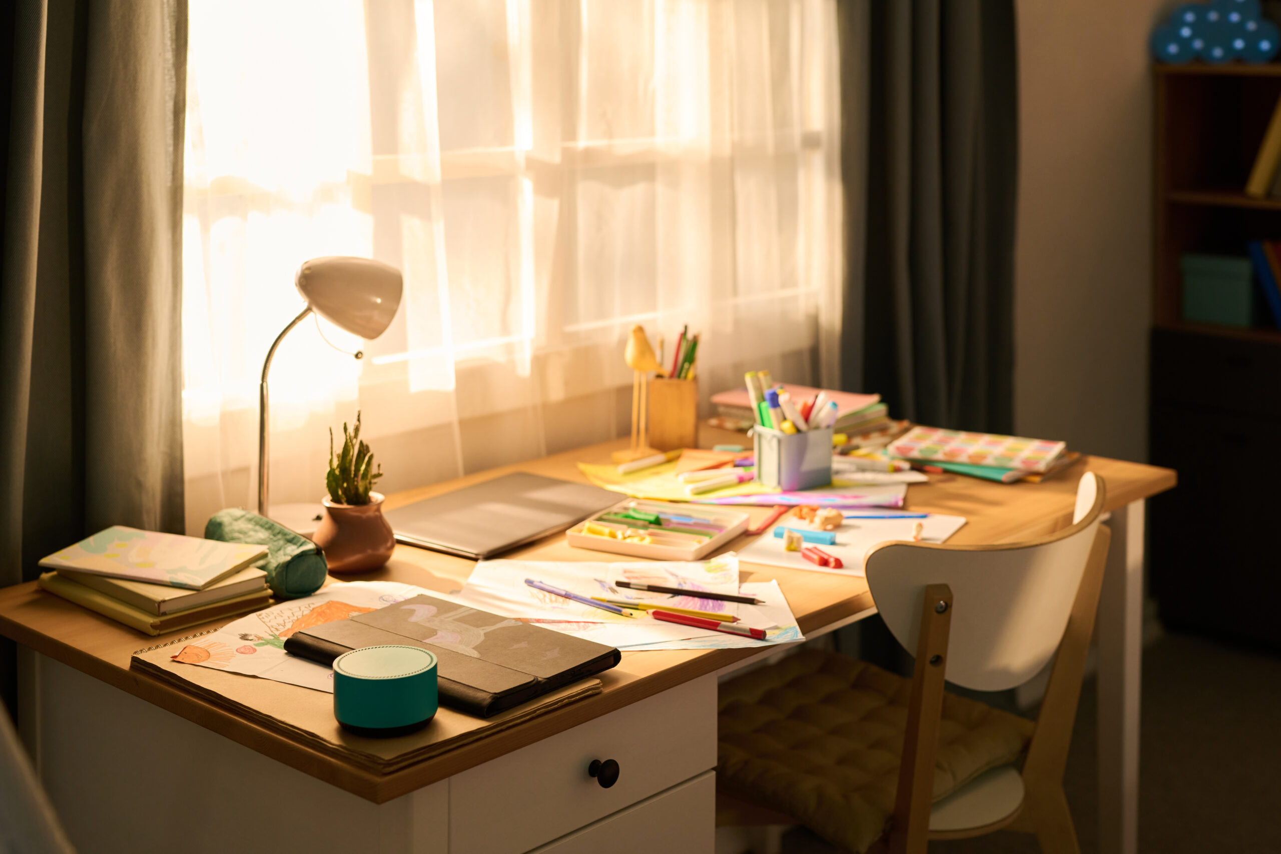empty study desk with school supplies and drawing materials in sunlit room