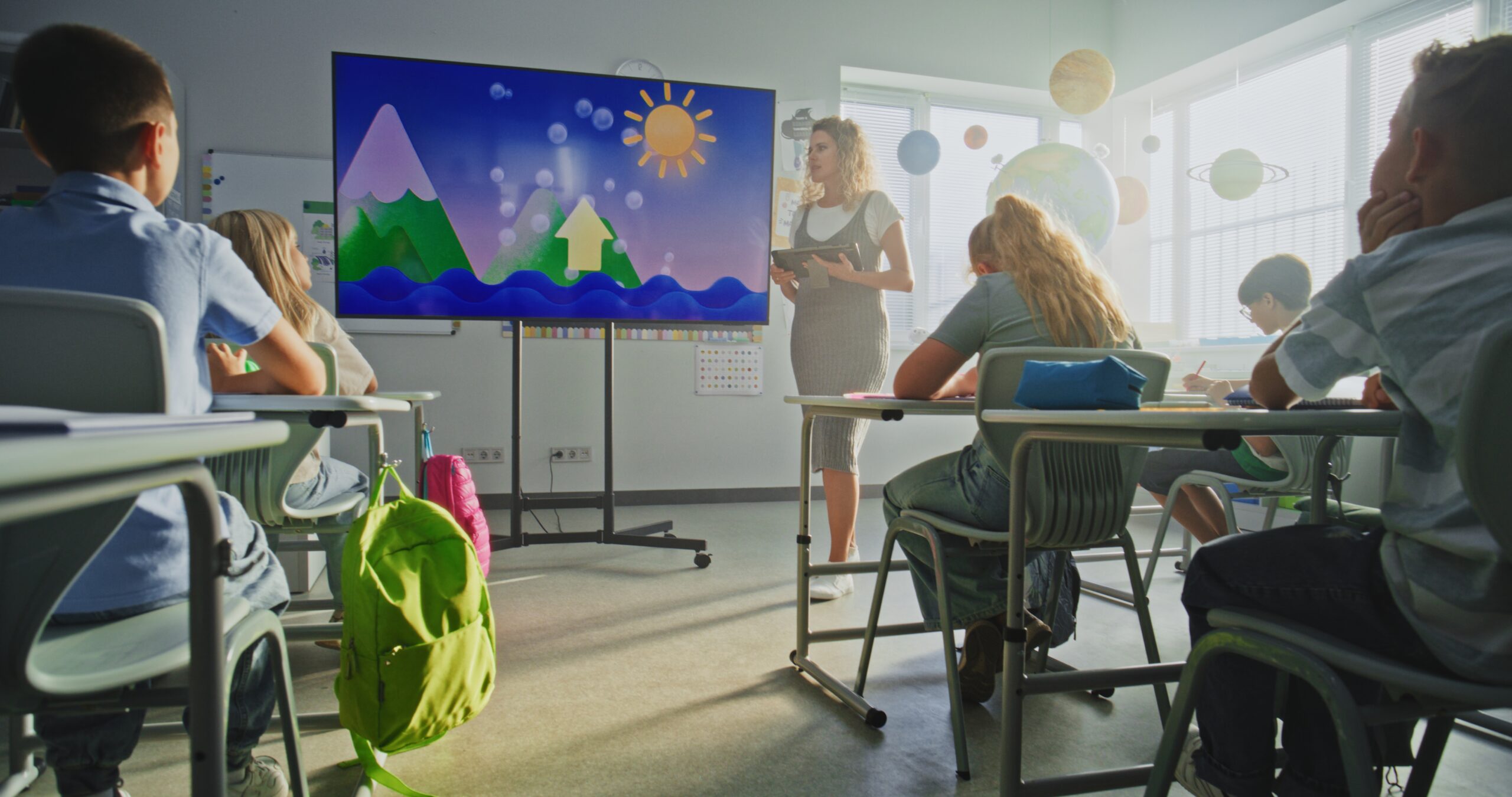female teacher with tablet computer explaining water cycles to kids using digital screen