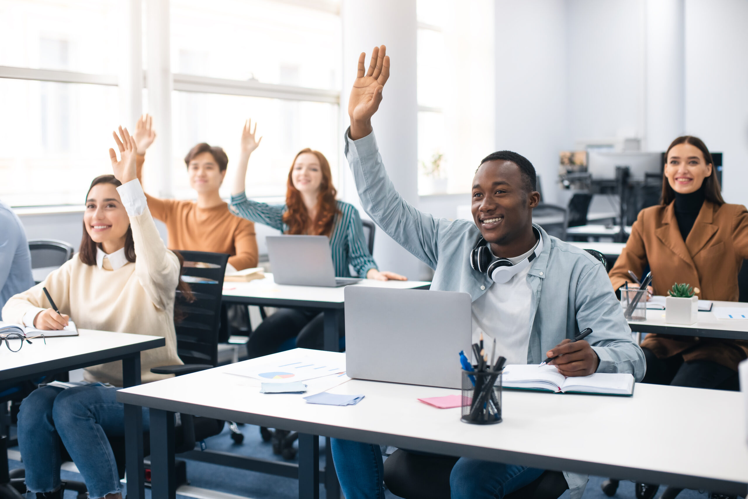 portrait of smiling diverse people raising hands at seminar