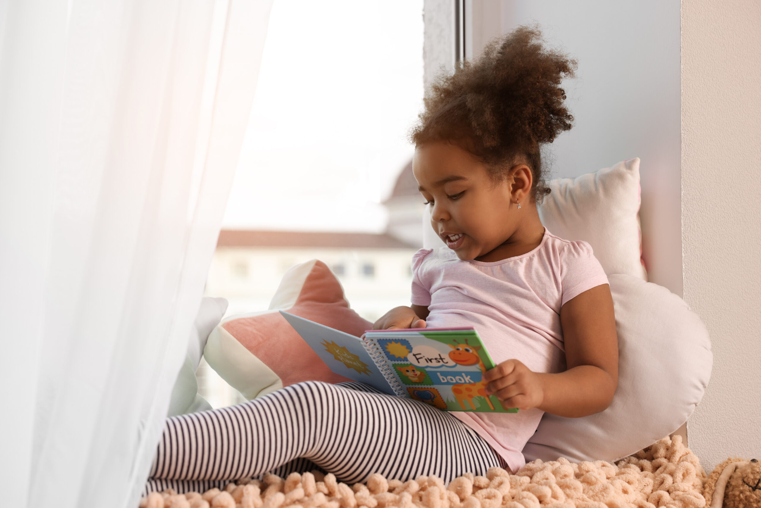 african american girl reading book at home