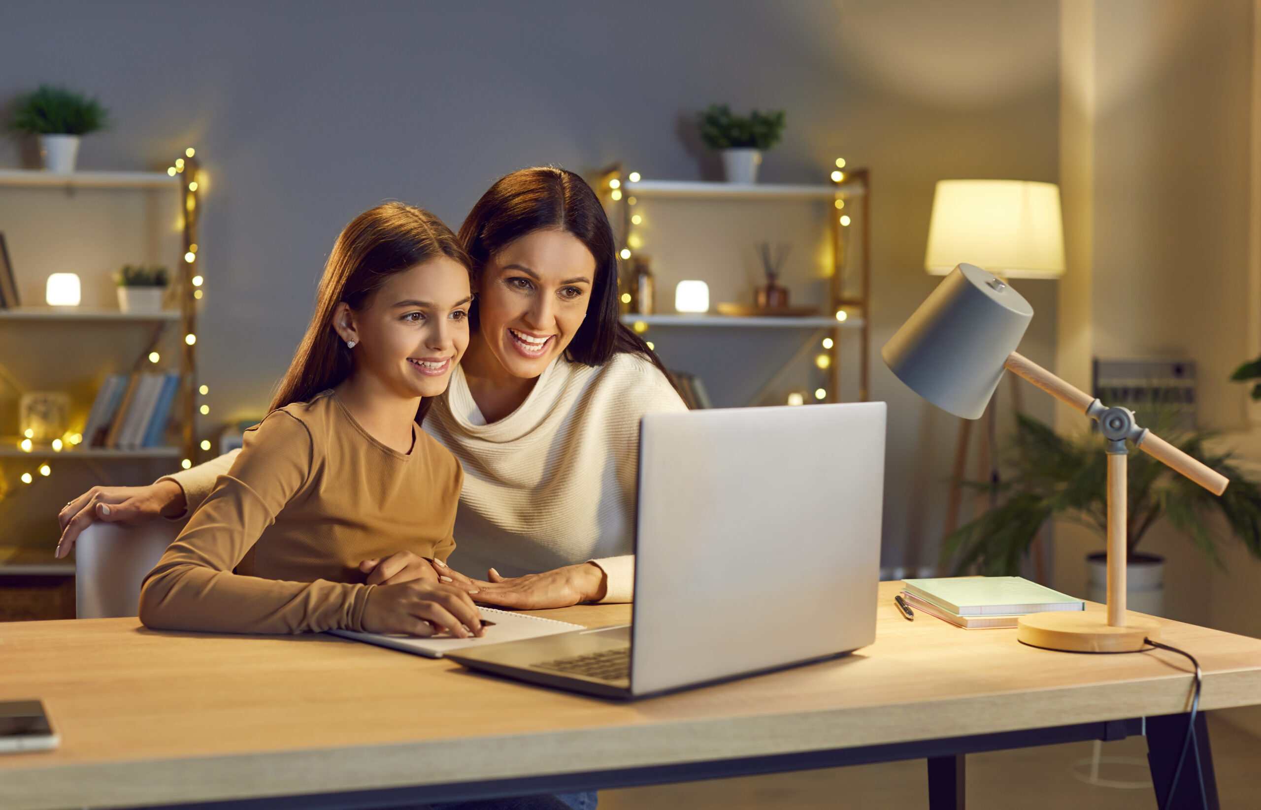 happy mother helping her child daughter with homework during remote lesson at home.