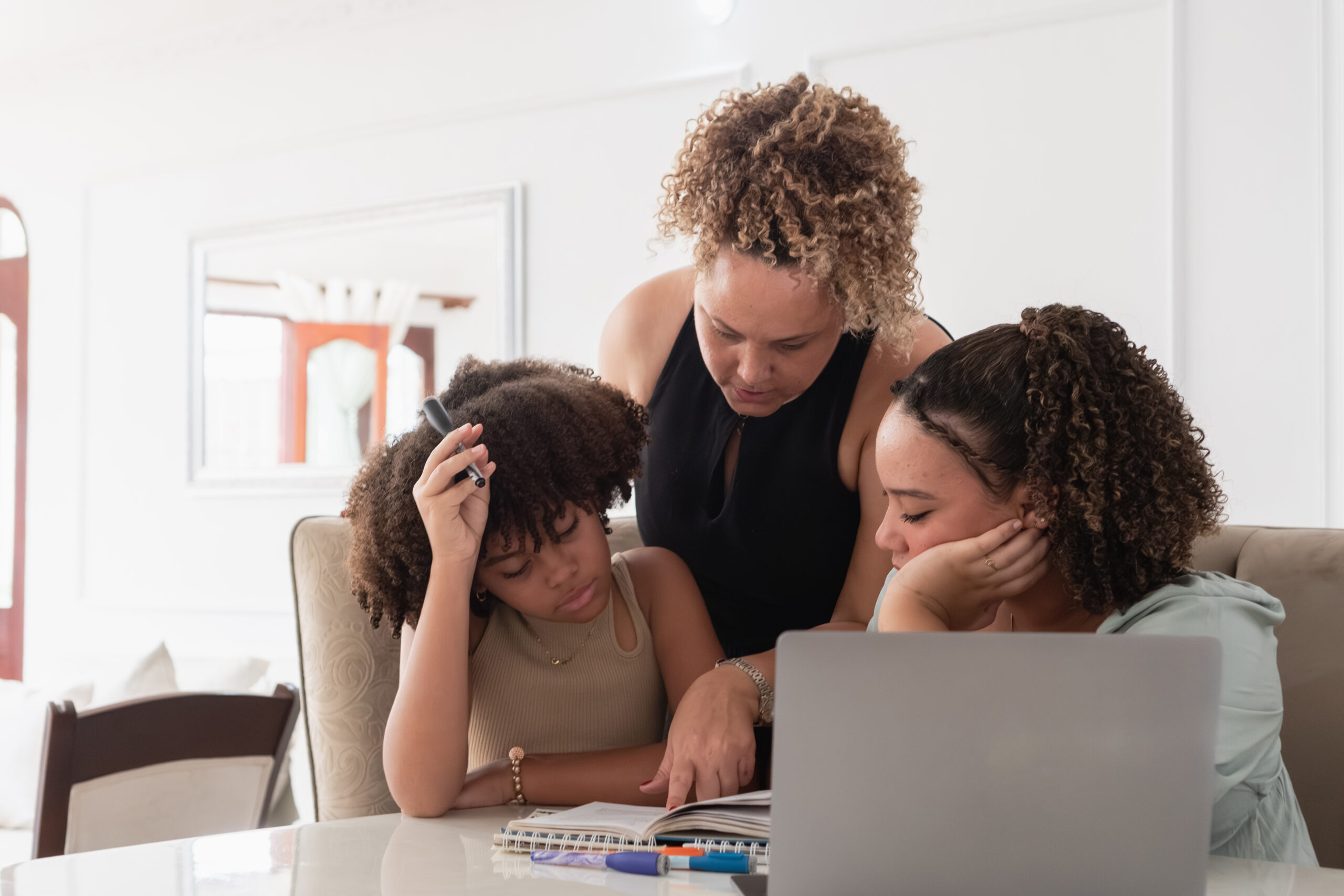 mother teaching daughters doing homework at home