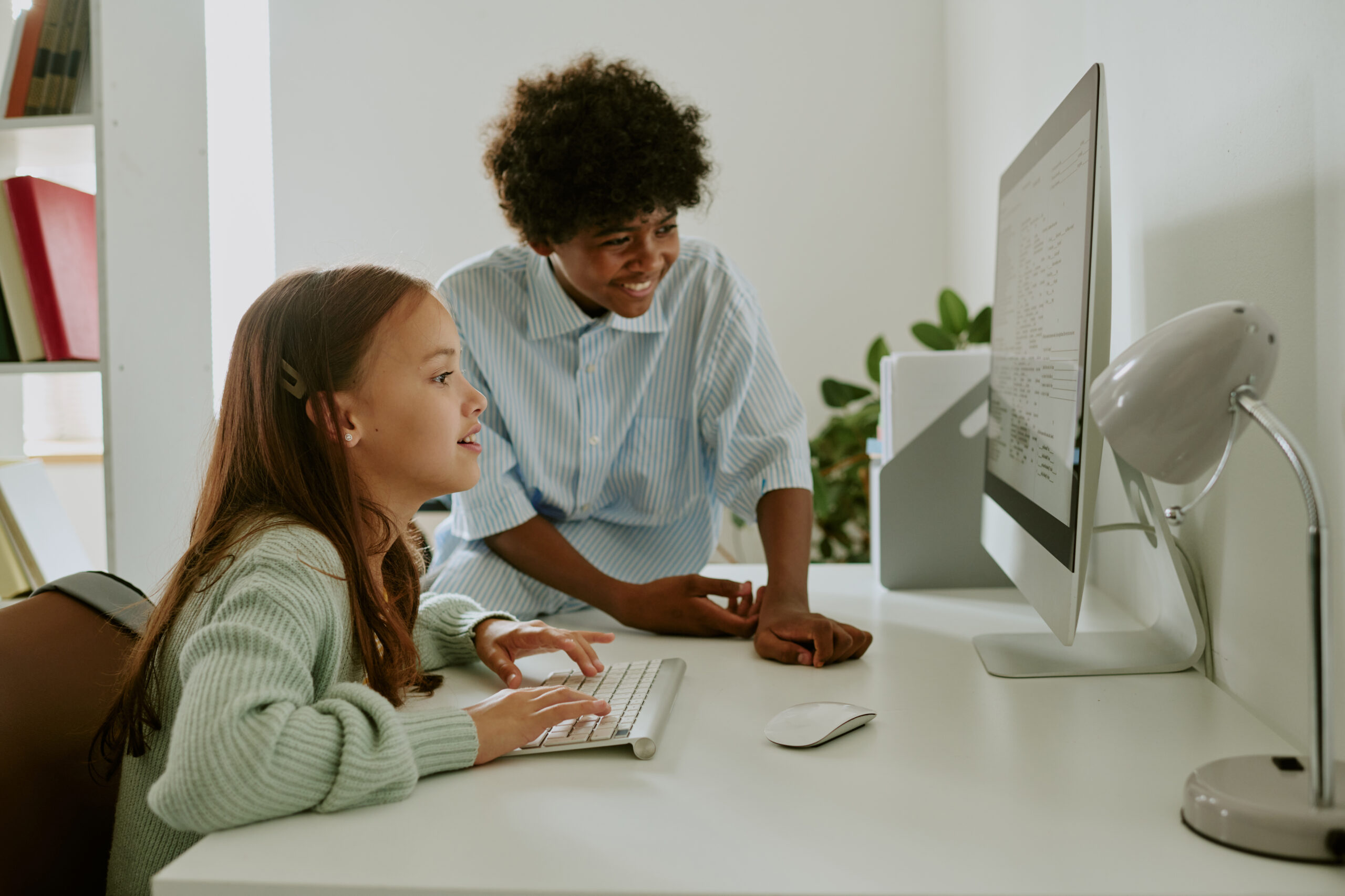 young caucasian girl and black teenager collaborating on computer project